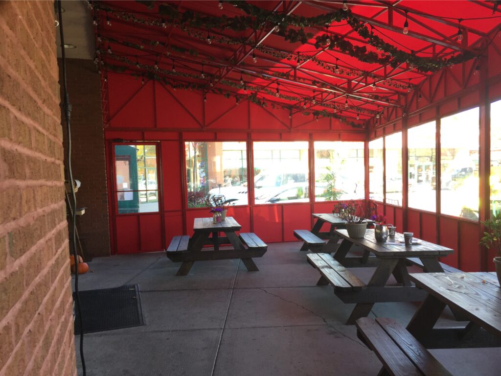 Outdoor dining area with picnic tables under a red canopy.