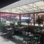 Cozy outdoor café seating area with tables and chairs under a canopy.
