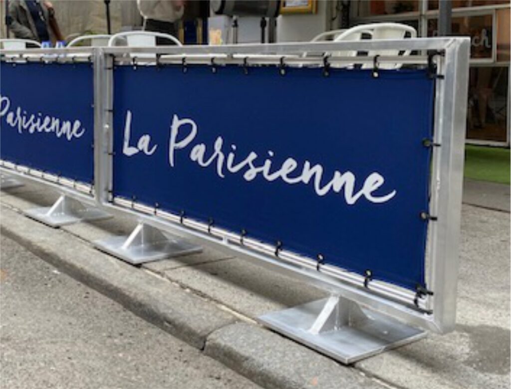 Blue barricade with 'La Parisienne' text on a street.