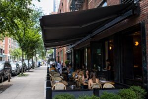Outdoor sidewalk cafe with patrons and awning