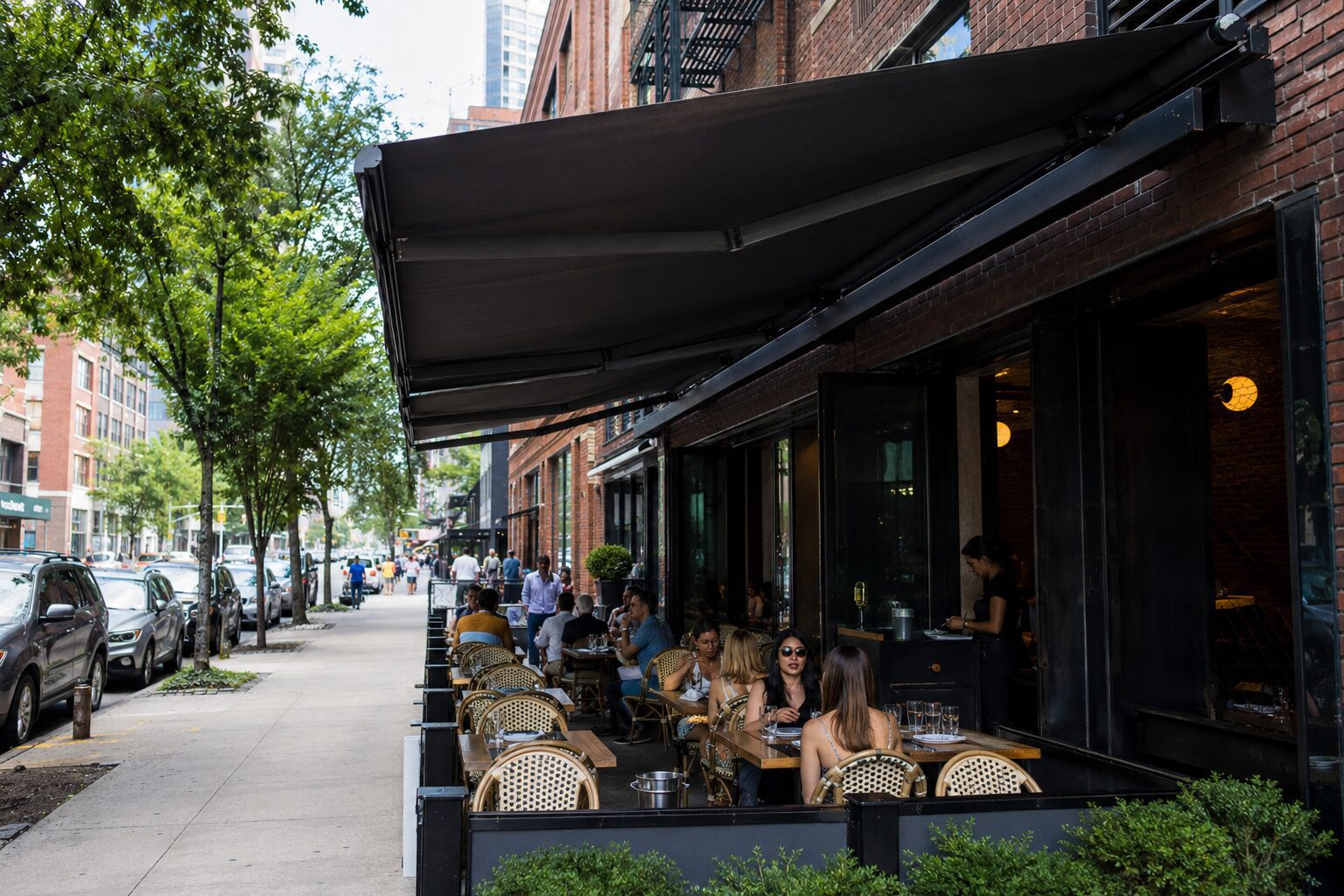 Outdoor sidewalk cafe with patrons and awning